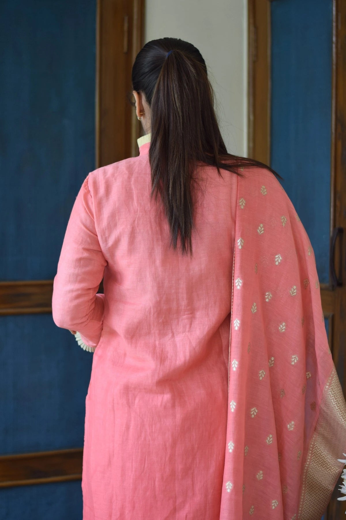 A woman in a flowy peach linen kurta with a simple round neckline.