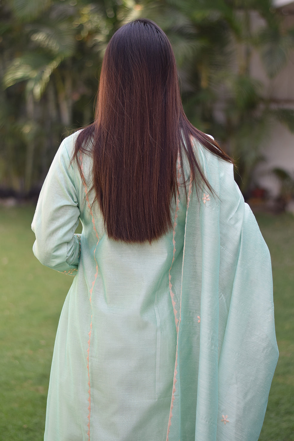 A woman wearing a sea green Aari work kurta with delicate floral embroidery