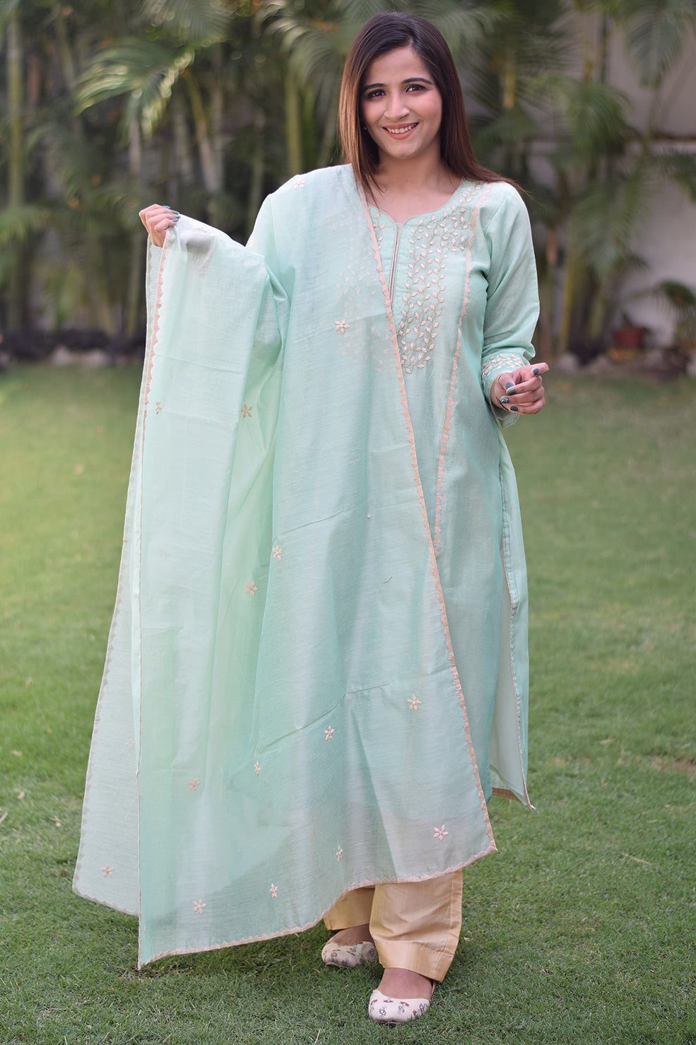 A woman wearing a sea green Aari work kurta with intricate embroidery