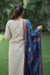 A solo woman models a beige kurta with a blue silk jamawar dupatta over one shoulder.