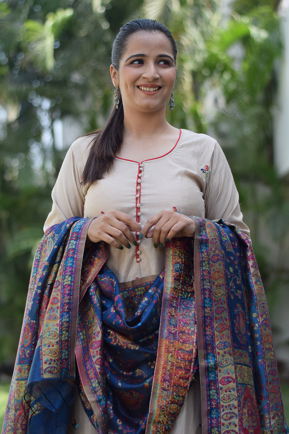 Solo female wears a beige kurta with a blue silk jamawar dupatta, looking elegant.