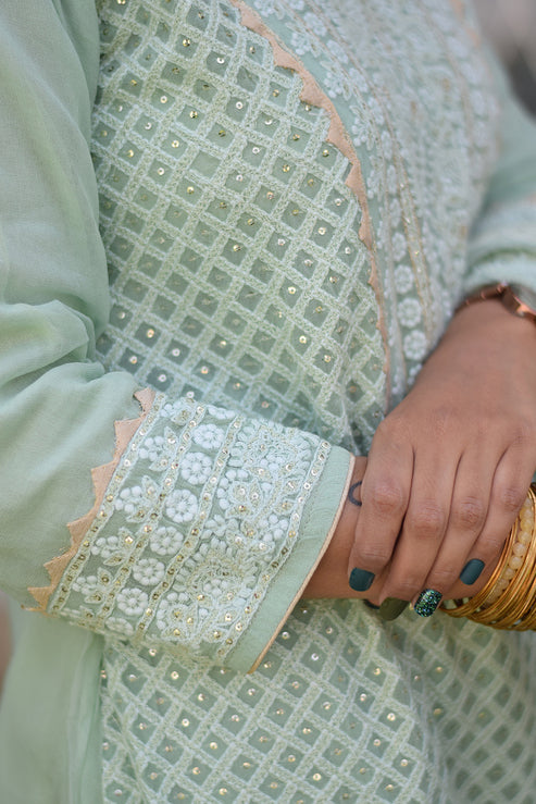 A woman wearing a green chikankari kurta set, showcasing Indian style.