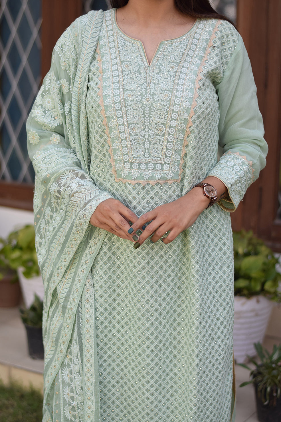 A stunning Indian woman showcasing a green chikankari kurta set with intricate embroidery.