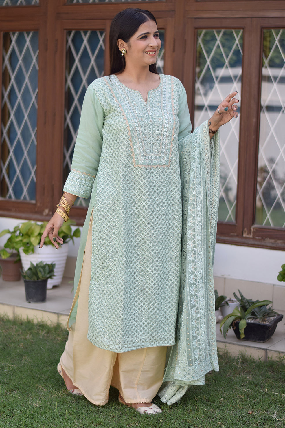 An elegant Indian lady dressed in a green chikankari kurta set.