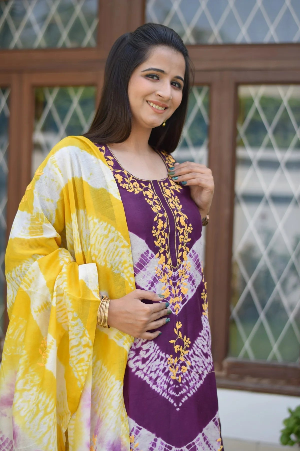 A fashionable and comfortable Indian outfit featuring a purple and yellow tie-dye kurta and dupatta with intricate embellishments, paired with yellow palazzo pants for a chic and trendy look.