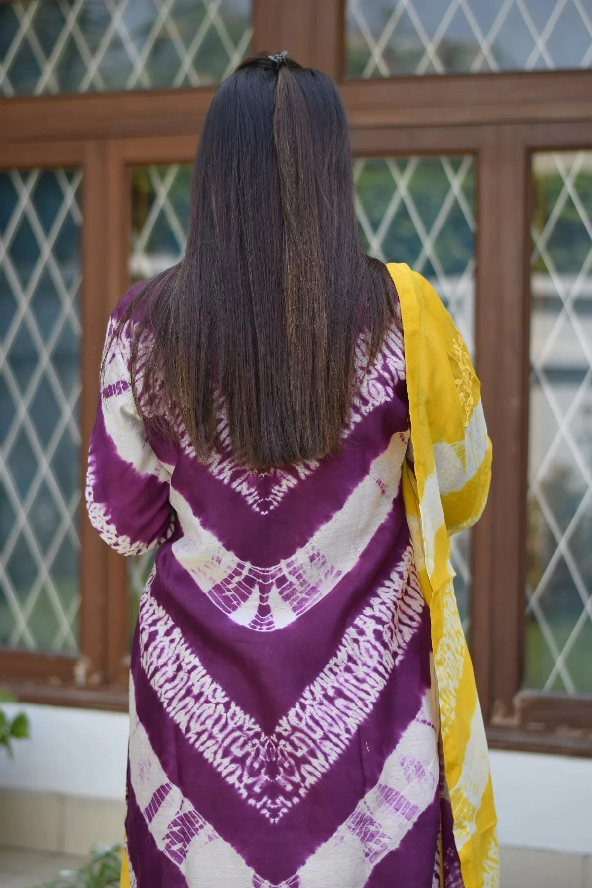 A stylish ensemble consisting of a colorful tie-dye kurta with intricate applique work and a complementing dupatta, worn with bright yellow palazzo pants.