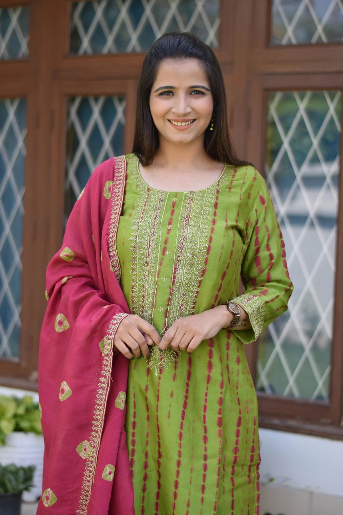 A woman wearing a stunning zari hand work suit with intricate golden embroidery.