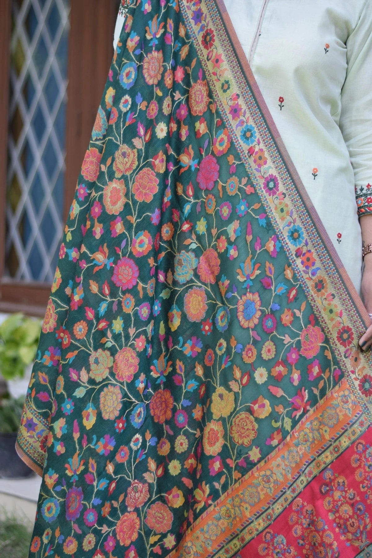 A green silk jamawar dupatta draped elegantly over a green chanderi resham embroidered kurta and palazzo.