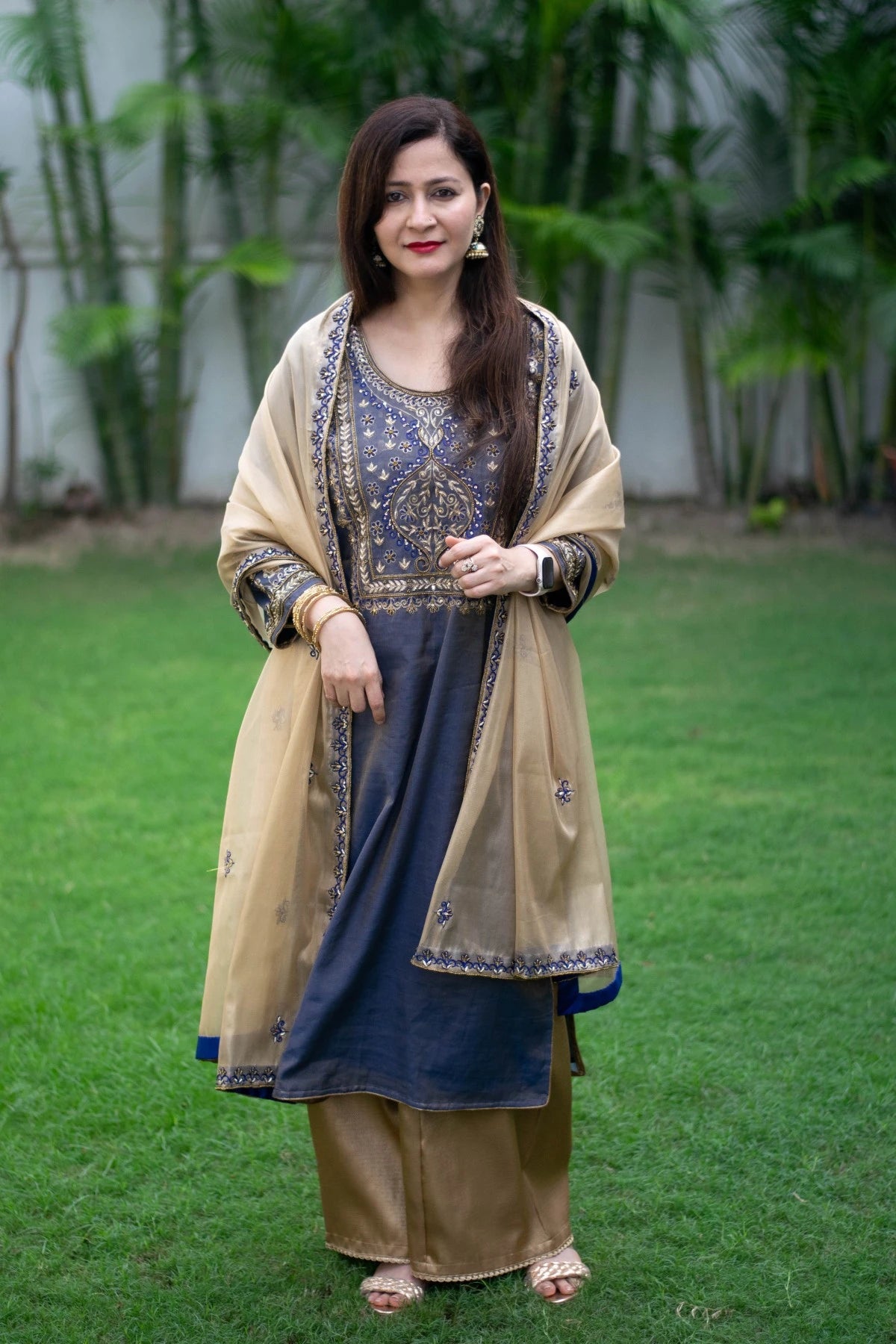 An elegant blue kurta with gold embroidery paired with a stunning gold tissue dupatta and palazzo pants, worn by a woman.