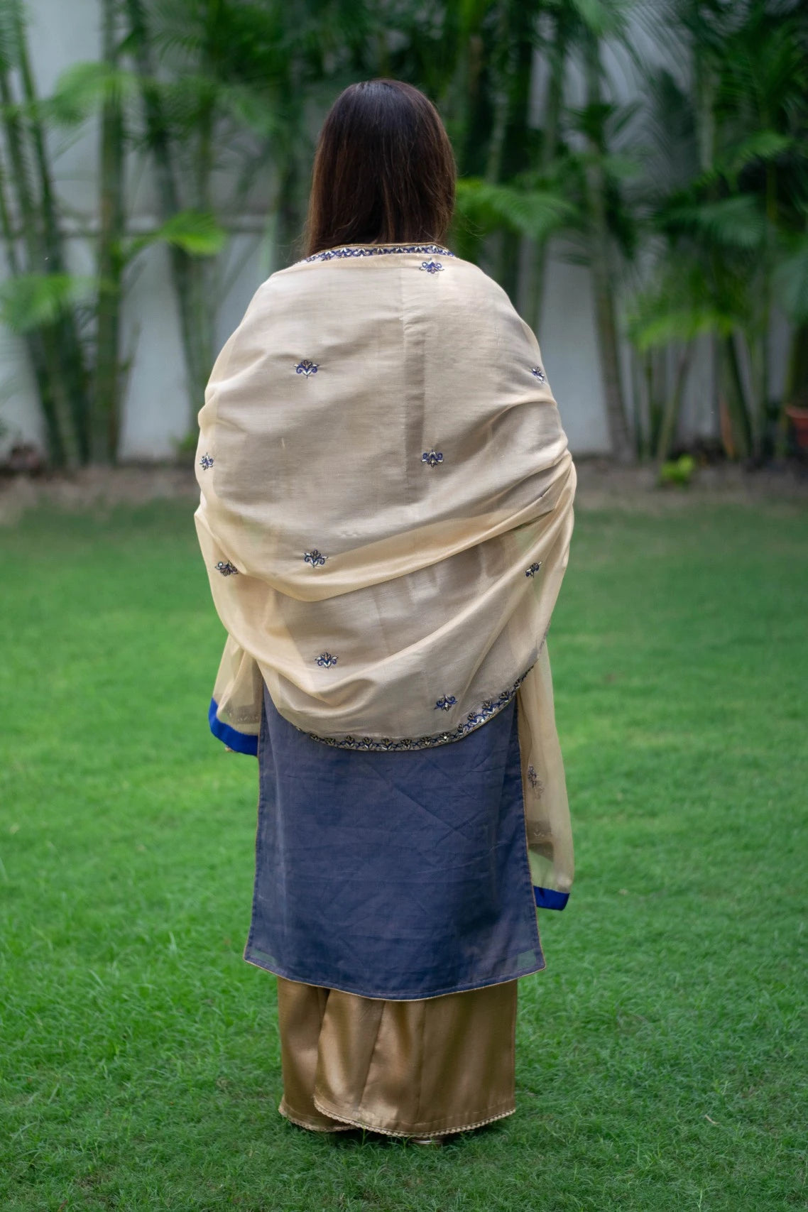 A stunning outfit featuring a blue kurta with gold embroidery, a gold tissue dupatta, and matching palazzo pants, worn by a woman.