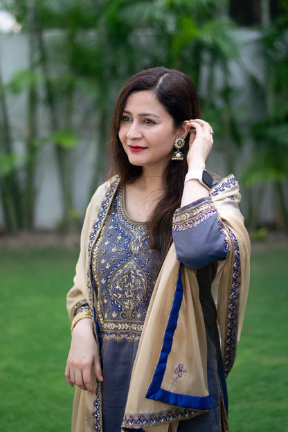 A stunning ensemble featuring a blue kurta with gold zardozi work, a gold tissue dupatta, and matching palazzo pants worn by a woman.