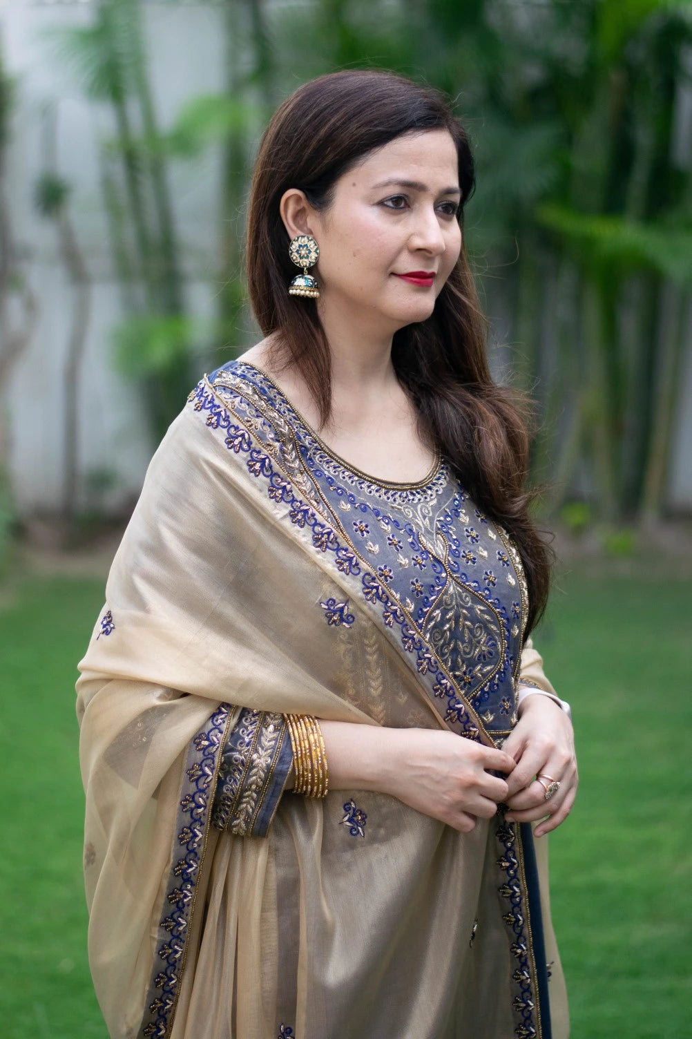 A beautiful blue kurta with intricate gold embroidery and a matching gold dupatta draped over the shoulders of a woman.