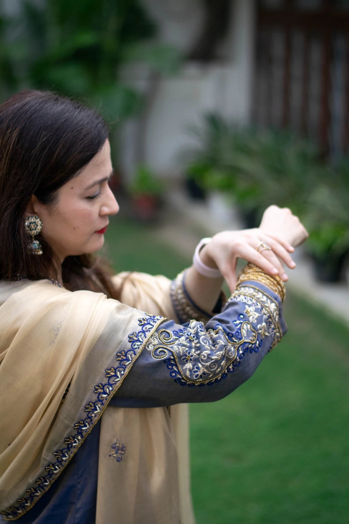 A beautiful ensemble featuring a blue kurta with gold zardozi work, a gold tissue dupatta, and matching palazzo pants worn by a woman with grace.