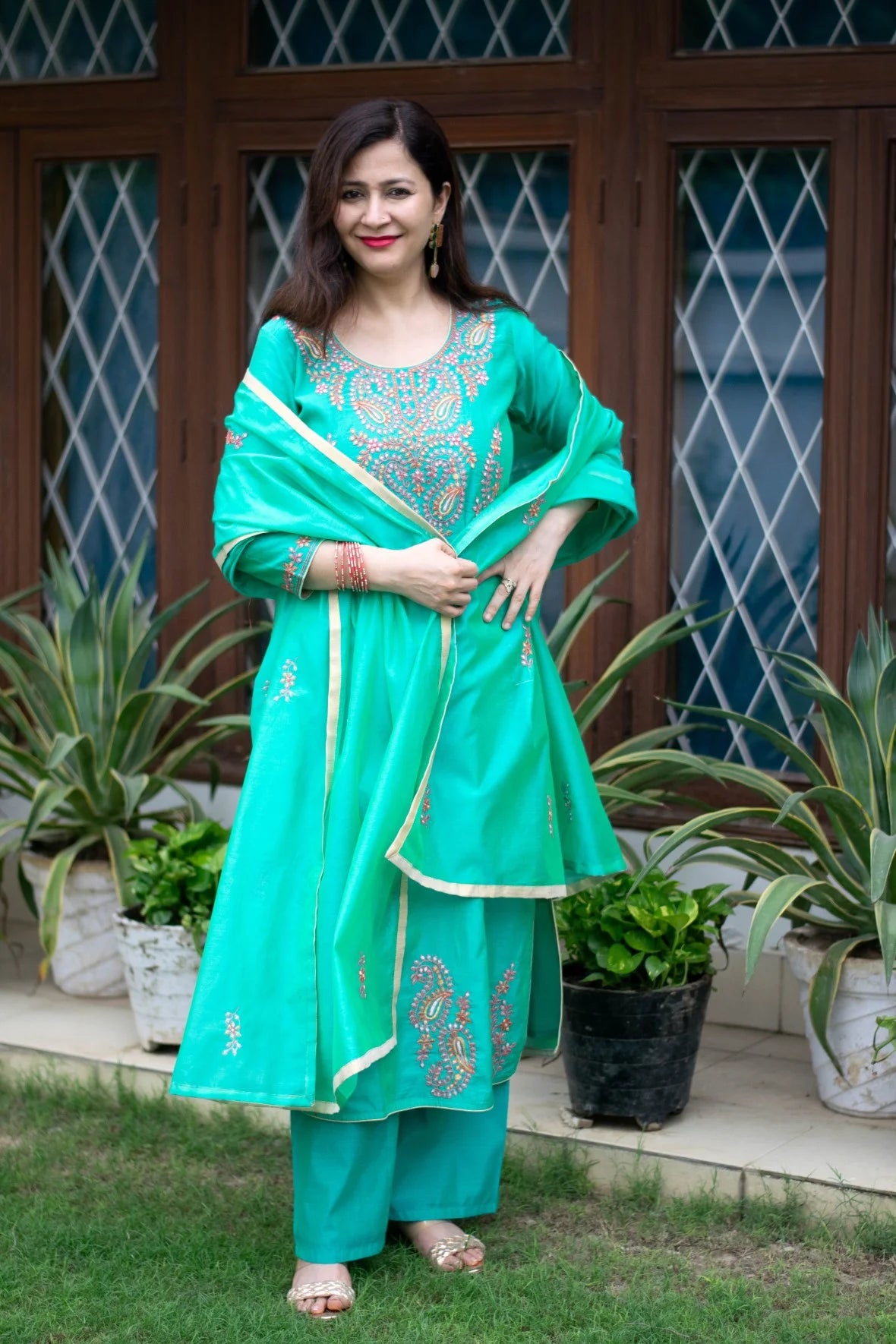 A woman wearing a sea green zari kurta with intricate embroidery.