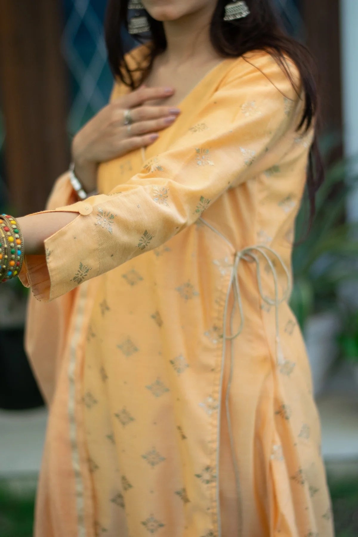 An Indian woman looks stunning in her peach angarkha kurta, featuring delicate gold embellishments.