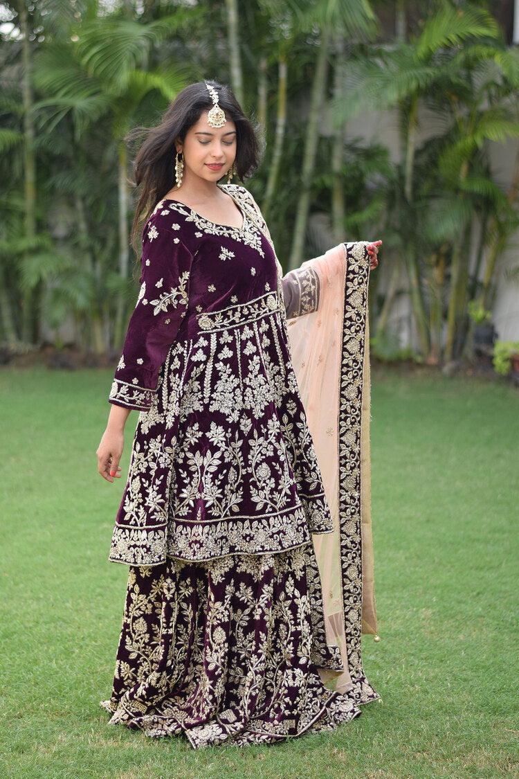 A stunning bridal lehenga set in wine velvet featuring opulent Zardozi work.