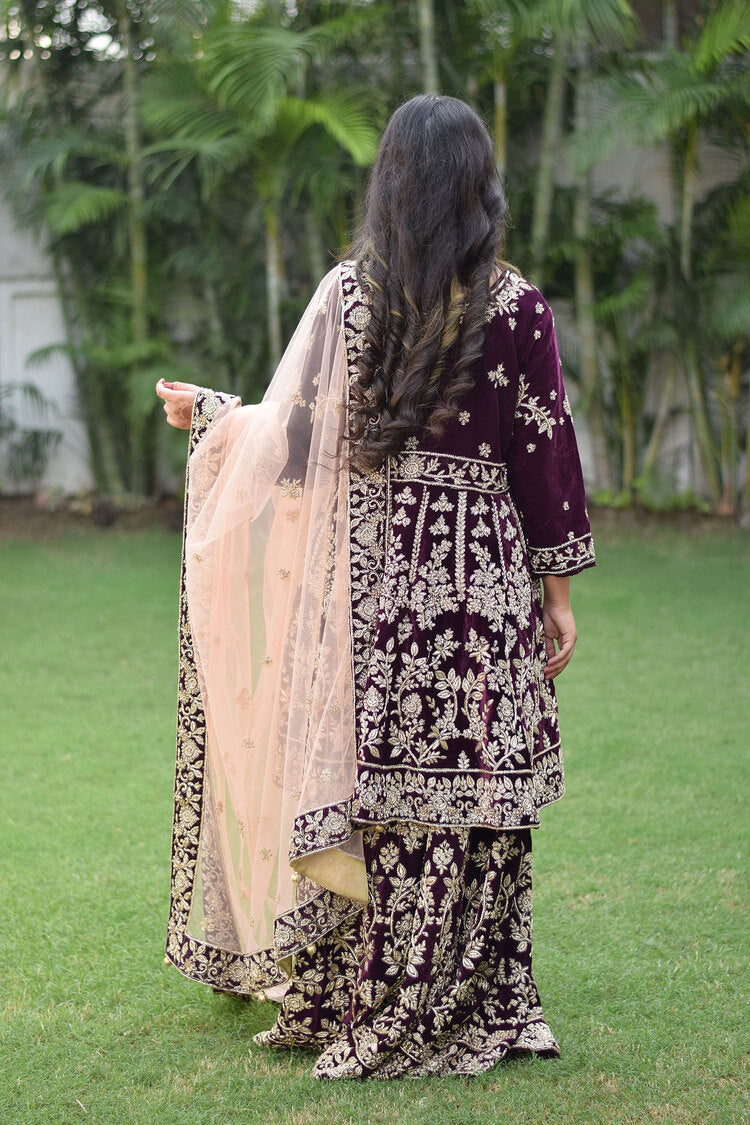A gorgeous Indian bride in a wine velvet lehenga set with intricate gold detailing.