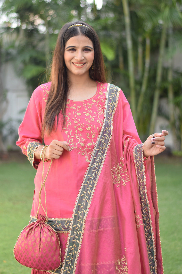 A woman wearing a fuchsia pink Chanderi Gharara set with intricate Aari and tissue applique work.