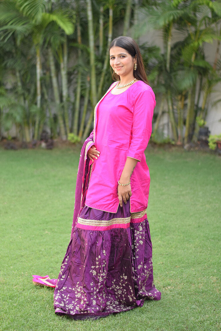 A beautifully dressed woman in a vibrant Purple and Magenta Silk Applique Gharara set.