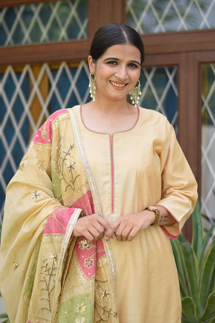 A woman wearing a pink and green patchwork Chanderi dupatta, paired with a golden kurta and palazzo pants.