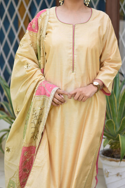 A woman dressed in a stunning pink and green patchwork Chanderi dupatta, complemented with a golden kurta and palazzo pants.