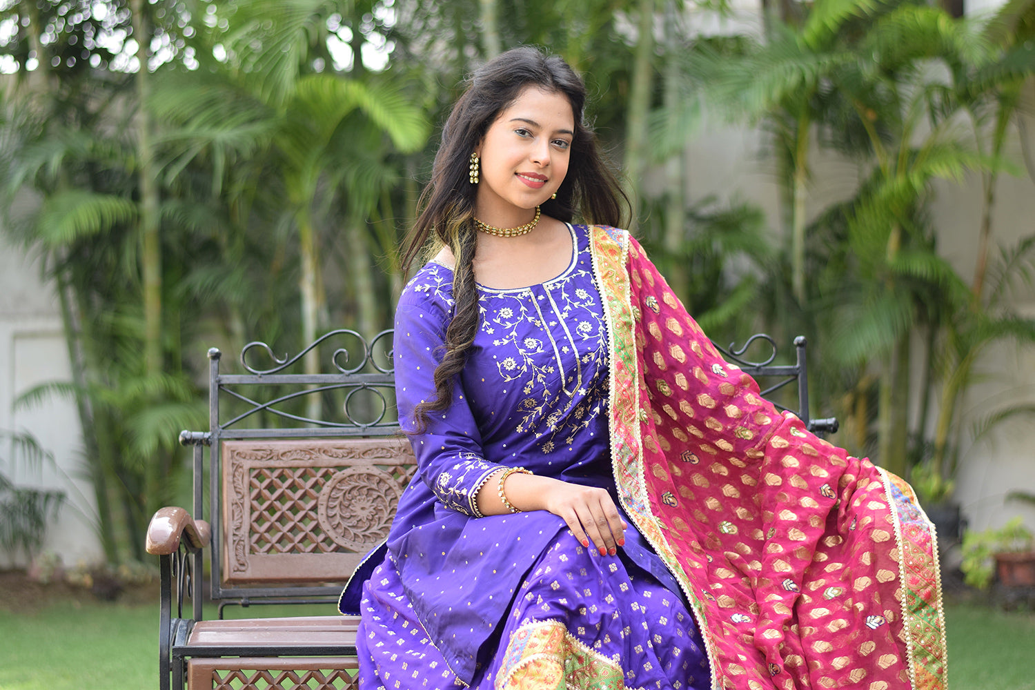 A woman sitting on a bench wearing Purple Silk & Multicolored Brocade Farshi Gharara Set