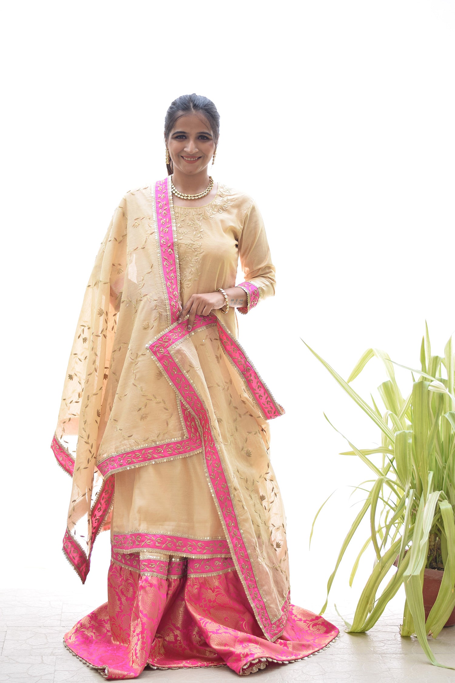 A woman wearing a beautiful Magenta Kamkhab Farshi Gharara, Golden Chanderi Kurta & Dupatta with Tissue Applique Work.