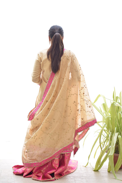 A stylish lady showcasing a Magenta Kamkhab Farshi Gharara, Golden Chanderi Kurta & Dupatta with Tissue Applique Work.