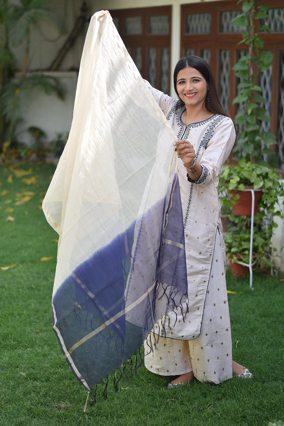 A stunning Indian woman wearing an Off-White Silk Kurta with golden embellishments.