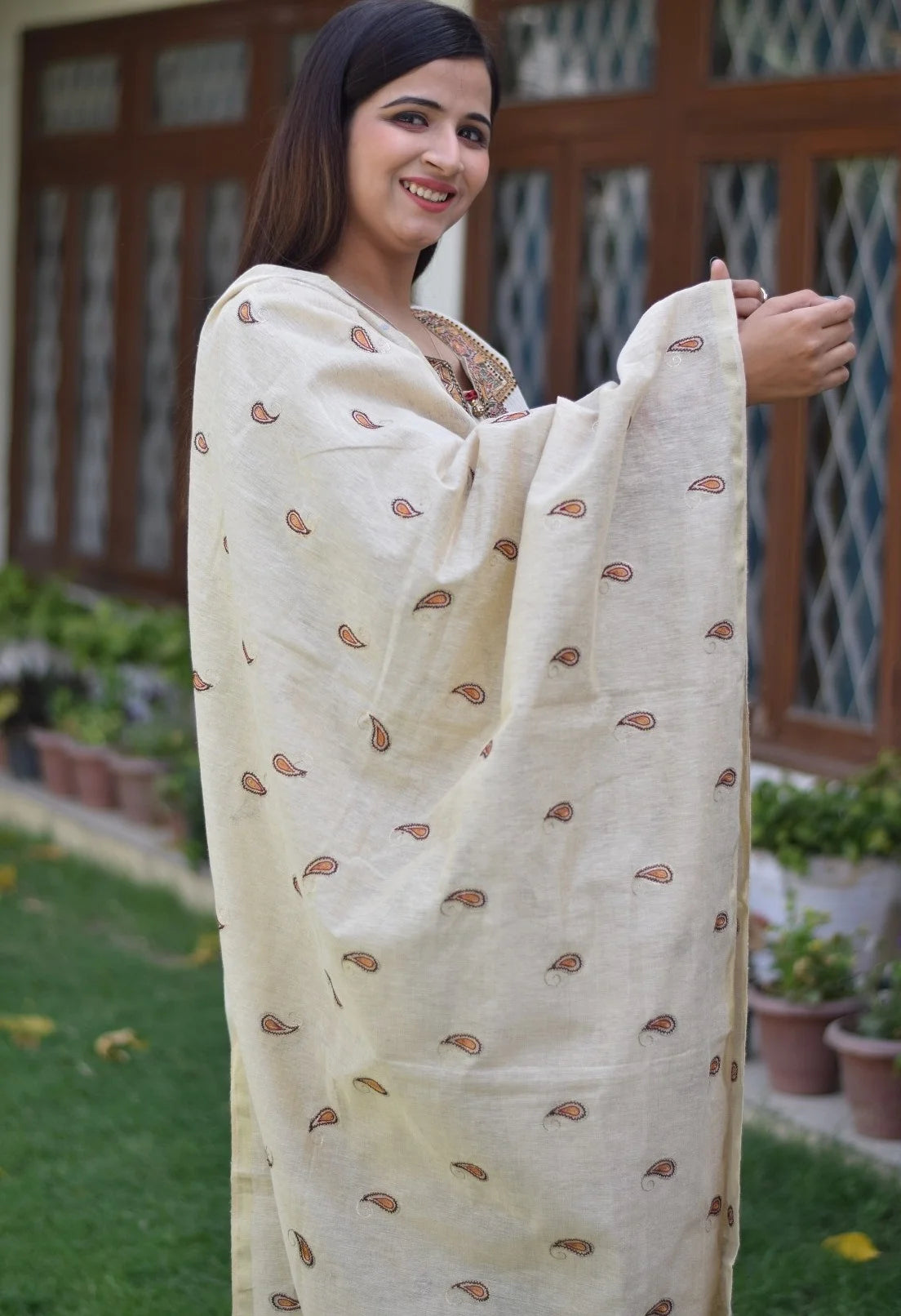 A trendy look of a woman wearing a beige chanderi kurta and dupatta with cropped beige trousers.