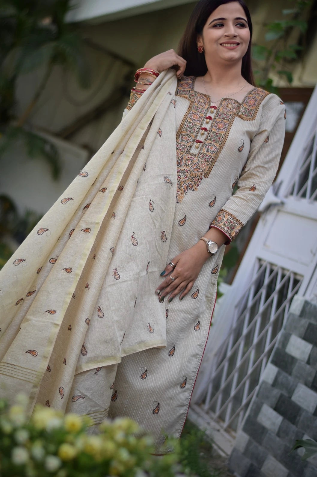 A woman wearing a beige chanderi kurta and dupatta with slim-fit beige trousers.