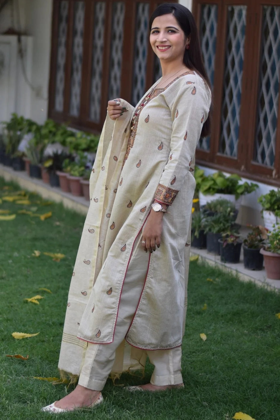 A full-length view of a woman wearing a beige chanderi kurta and dupatta with beige trousers.