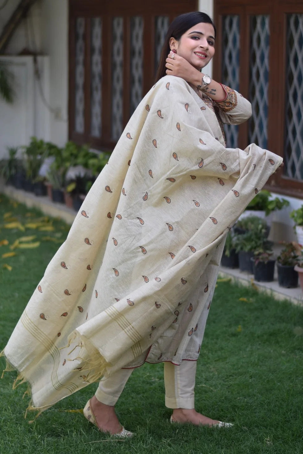 A woman wearing a beige chanderi kurta and dupatta with ankle-length beige trousers.