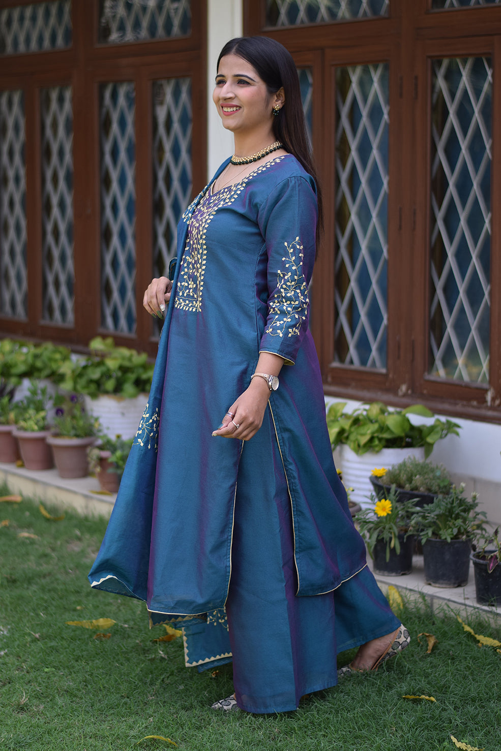 An Indian woman posing in a blue applique work suit with a serene expression.