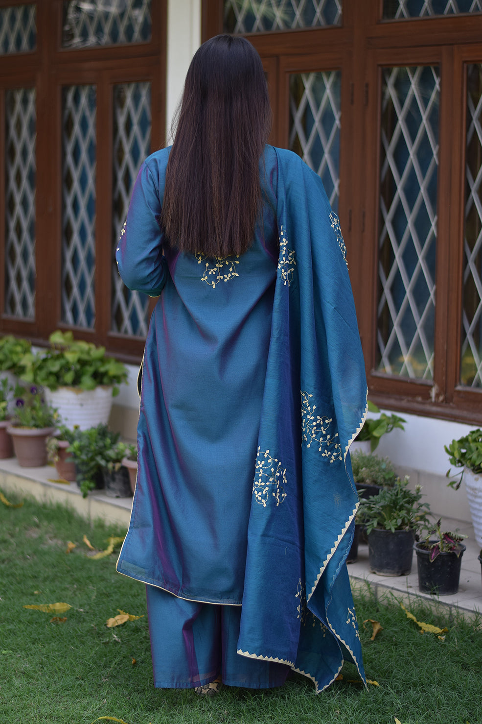An elegant Indian woman wearing a stunning blue suit adorned with applique work.