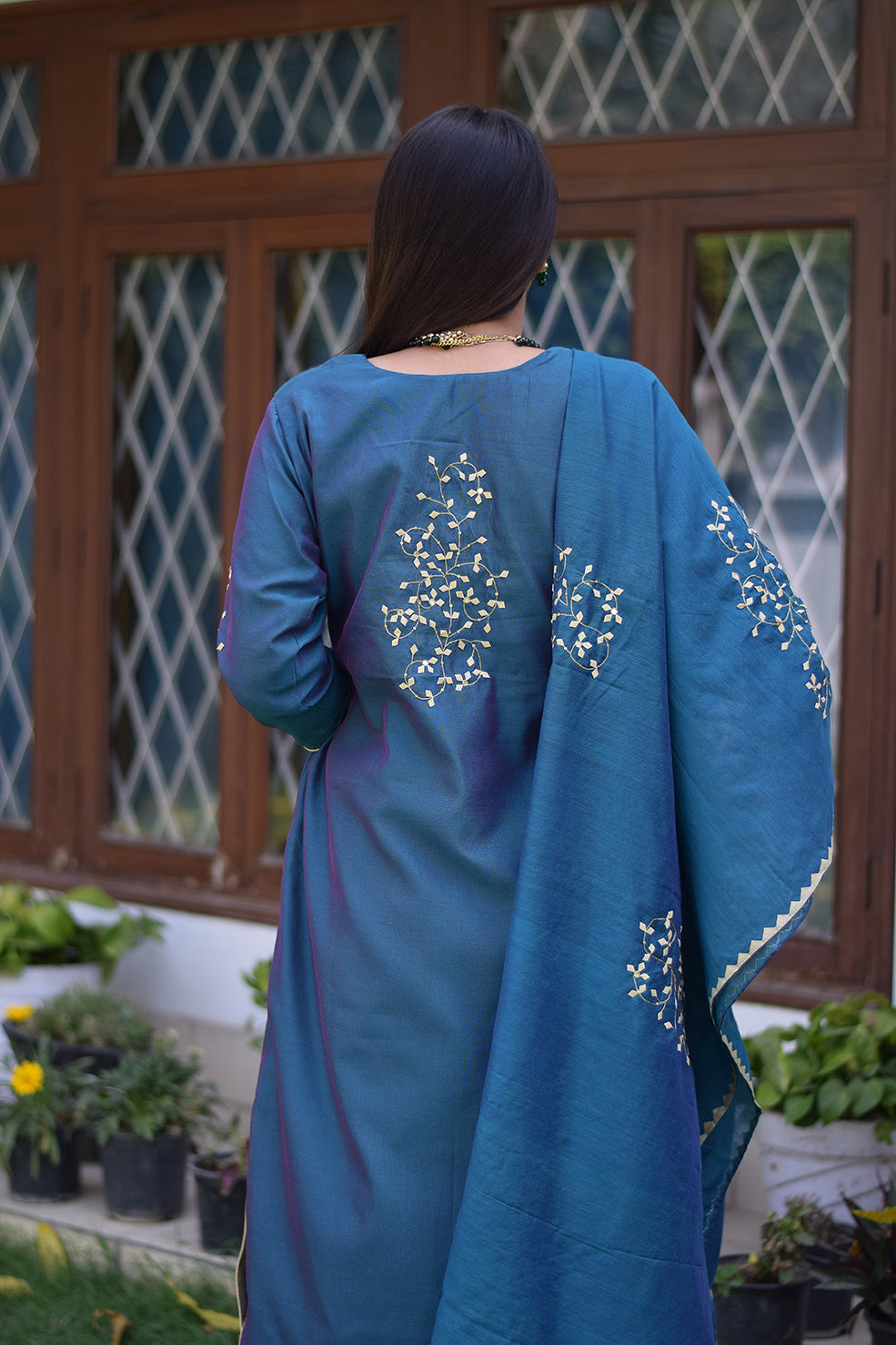 An attractive Indian woman dressed in a blue applique work suit and sporting a serene smile.