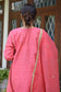 A stunning Indian woman wearing a vibrant pink jute kurta and churidar.