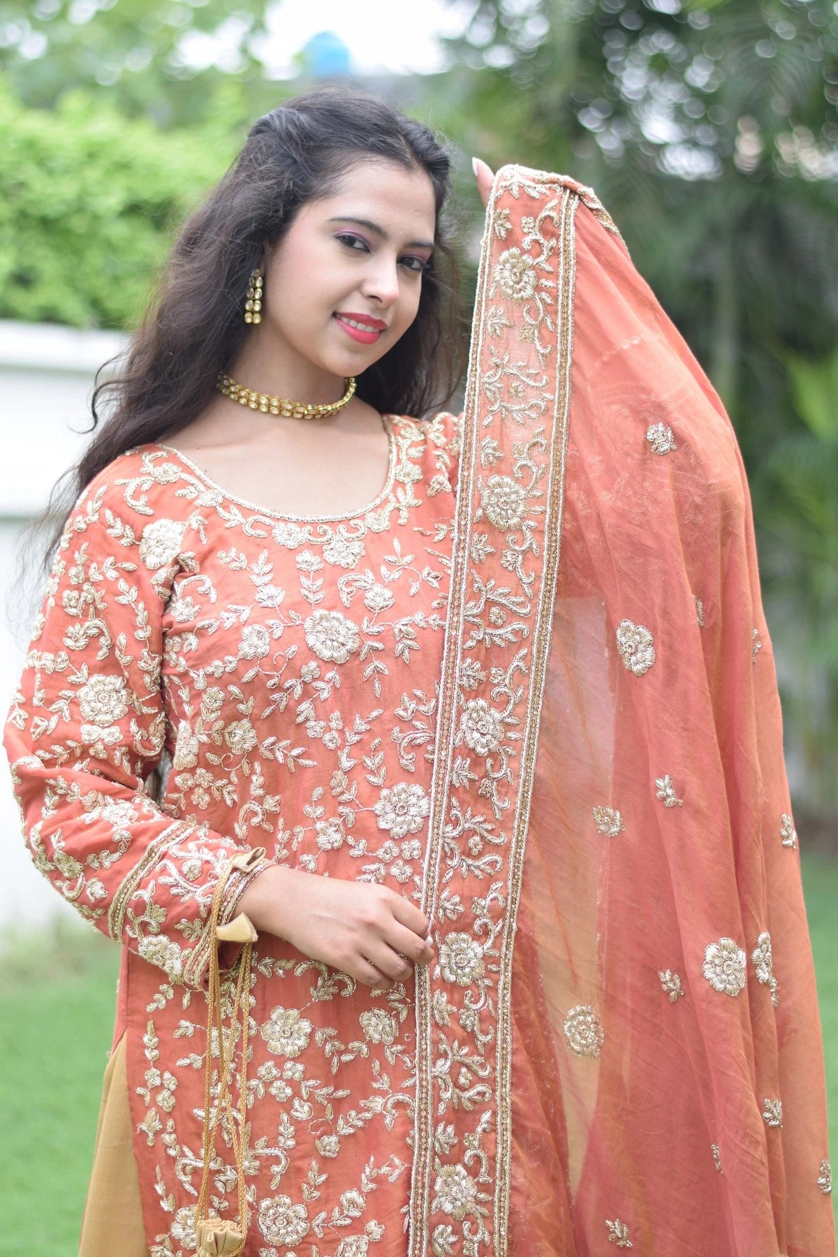 A stylish lady in a trendy farshi gharara with stunning golden rust embellishments.