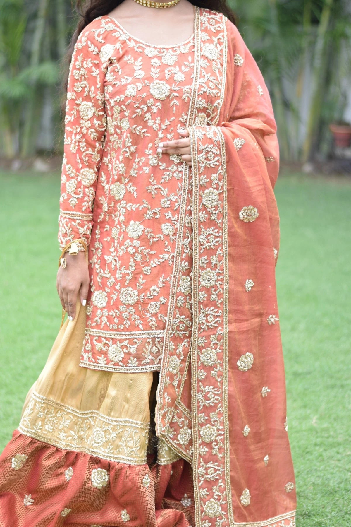 A lady in a stunning farshi gharara with intricate golden rust detailing, perfect for any formal occasion.