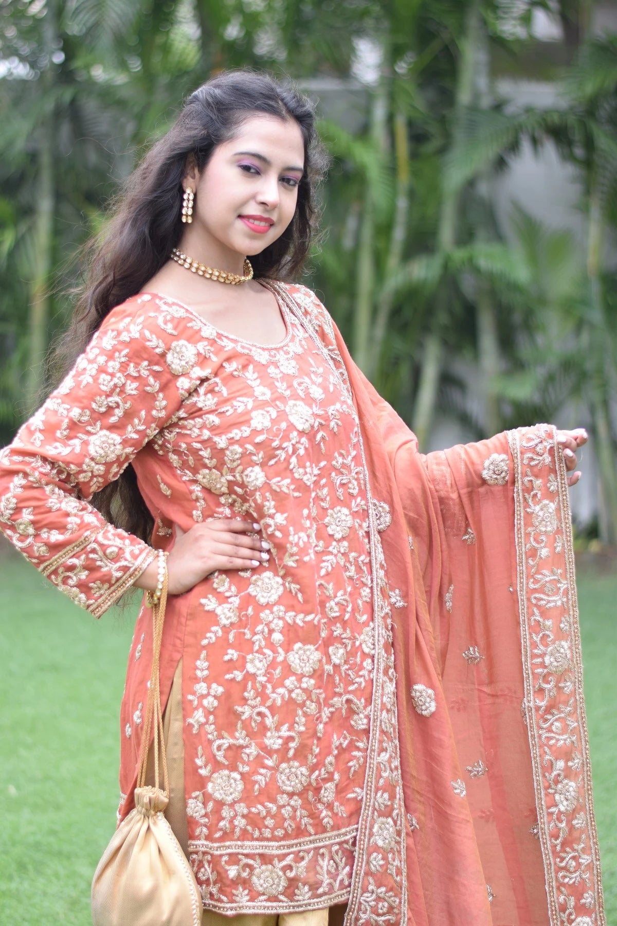 A woman in a timeless farshi gharara adorned with golden rust motifs.