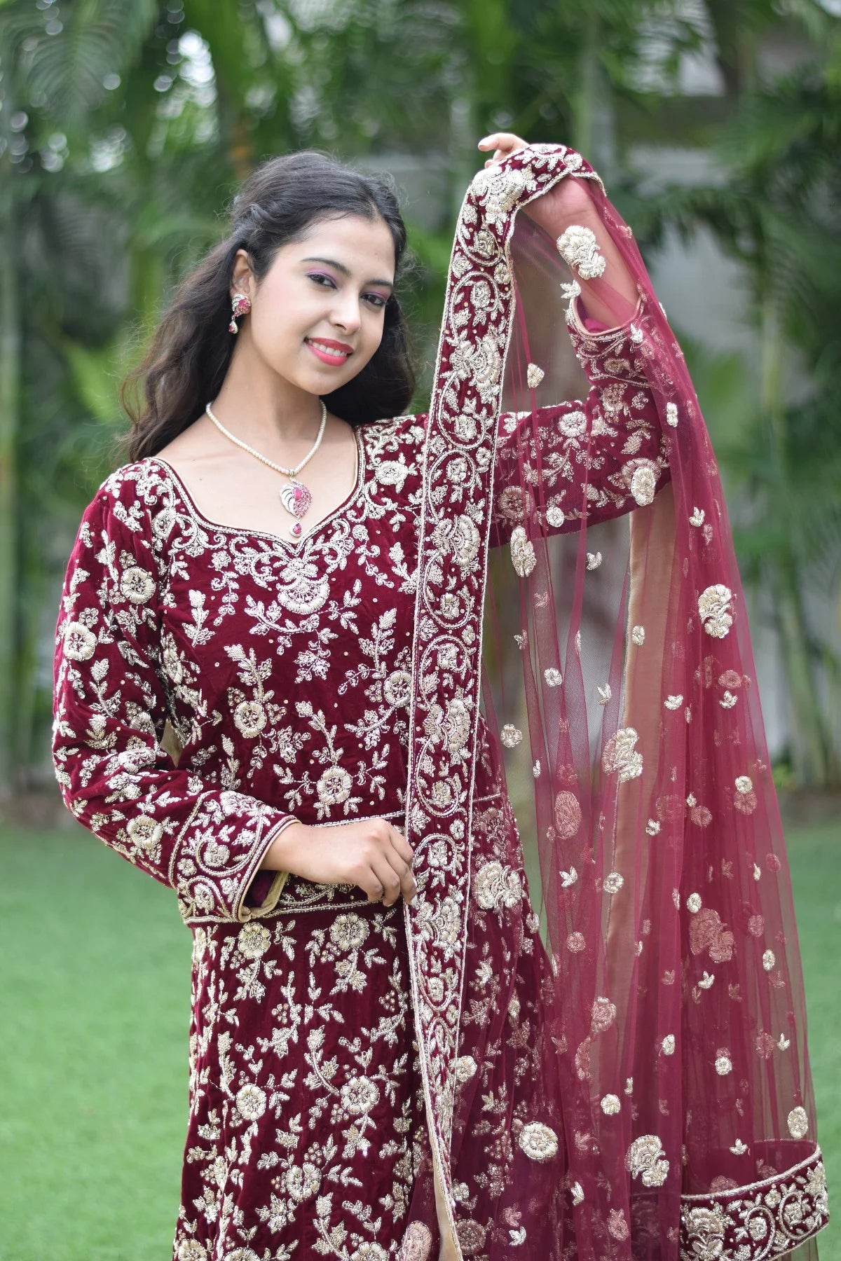 This Indian woman radiates confidence and grace in her maroon Trail Gown, which is sure to turn heads at any event.