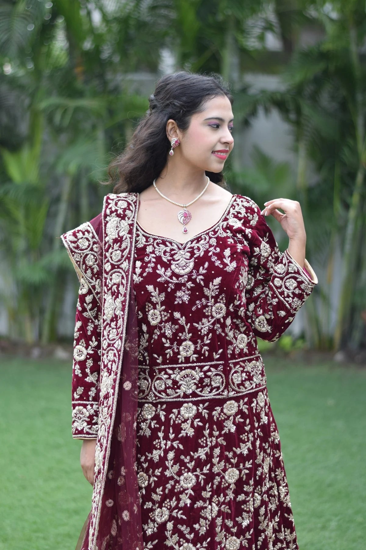 This Indian woman looks like royalty in her maroon Trail Gown, featuring a flowing train and ornate embellishments.