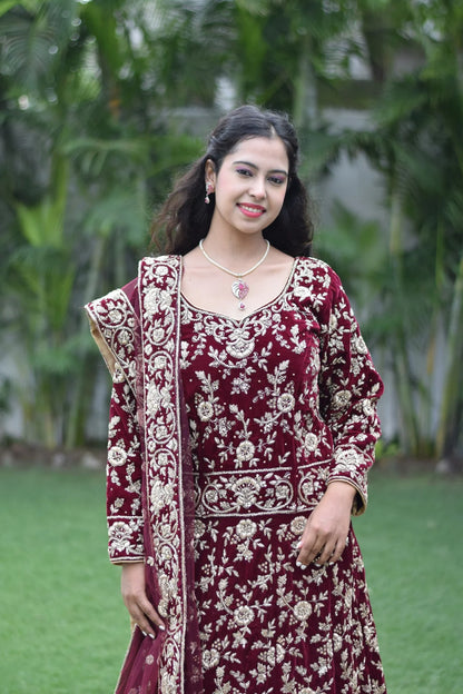 A maroon Trail Gown adorns an Indian woman, highlighting the intricate embroidery and elegant design.