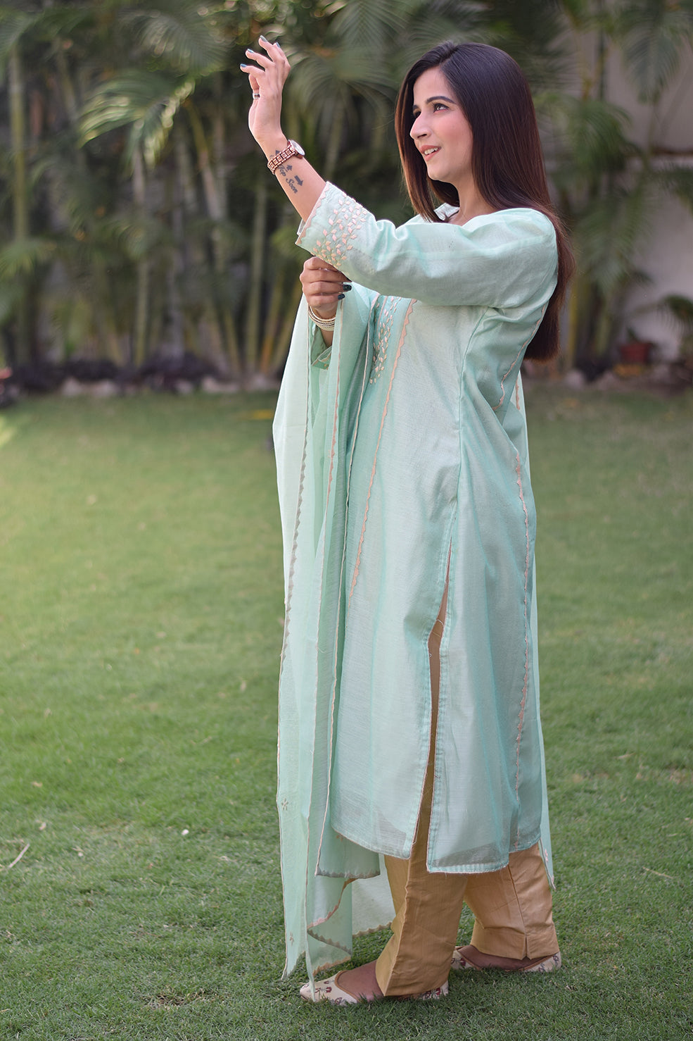 A woman wearing a sea green Aari work kurta with a scalloped hemline