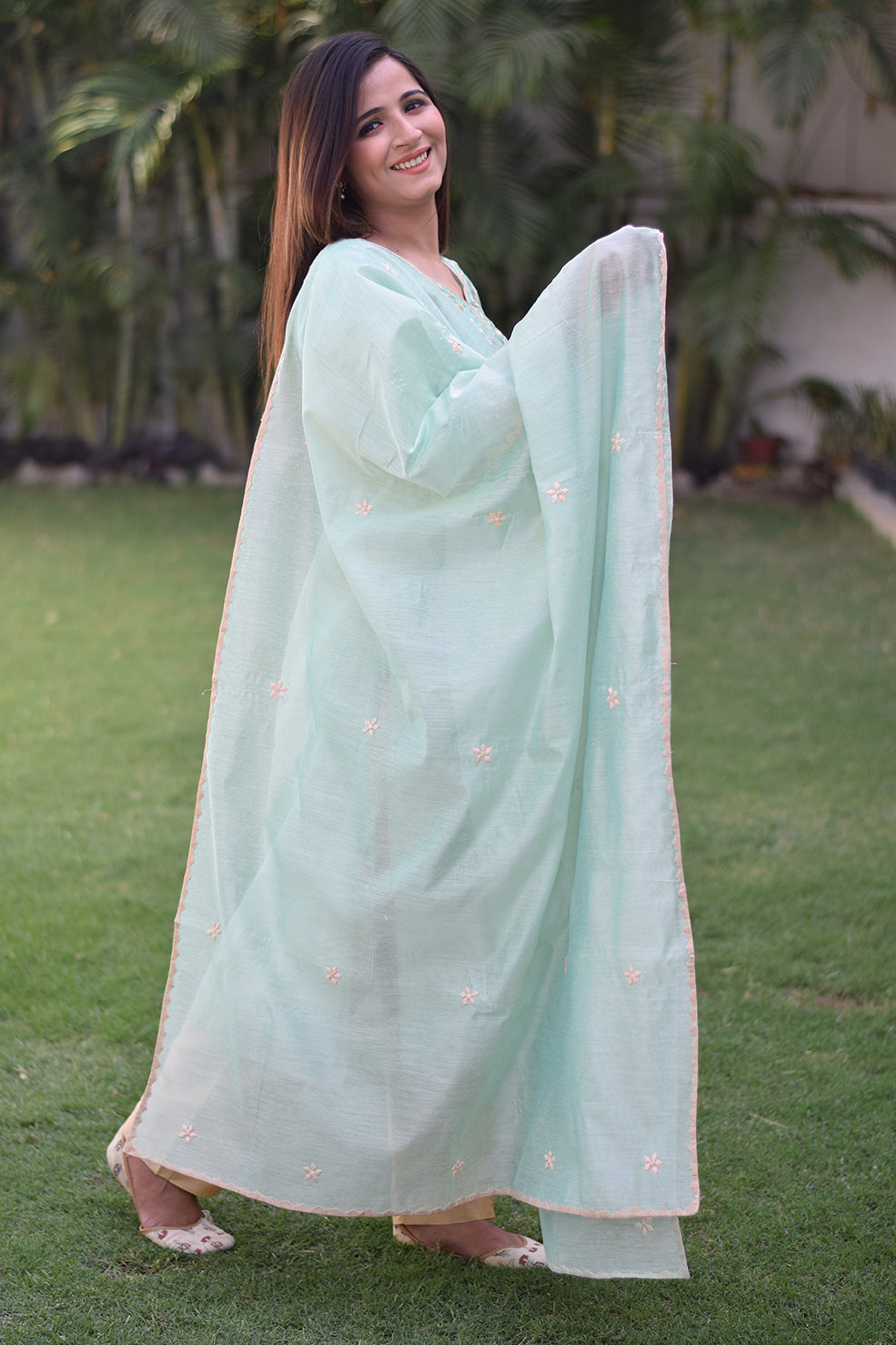 An Indian woman dressed in a sea green Aari work kurta with bell sleeves