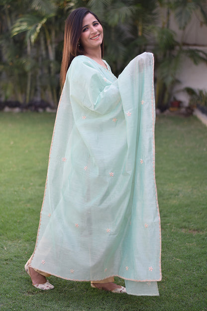 An Indian woman dressed in a sea green Aari work kurta with bell sleeves