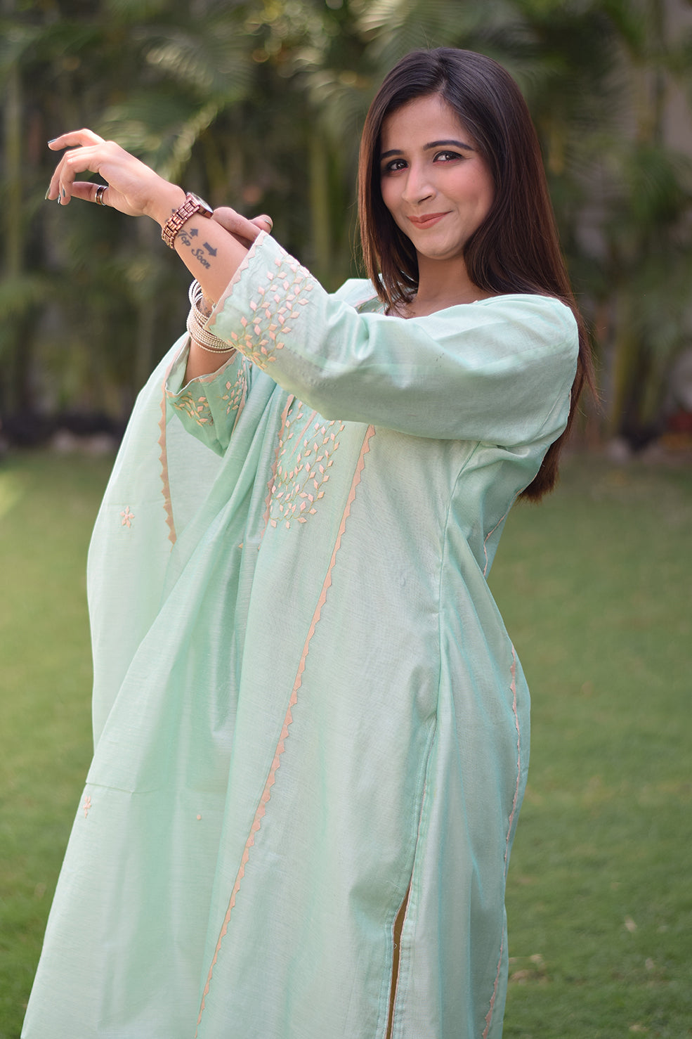 An elegant Indian woman in a sea green Aari work kurta with golden accents