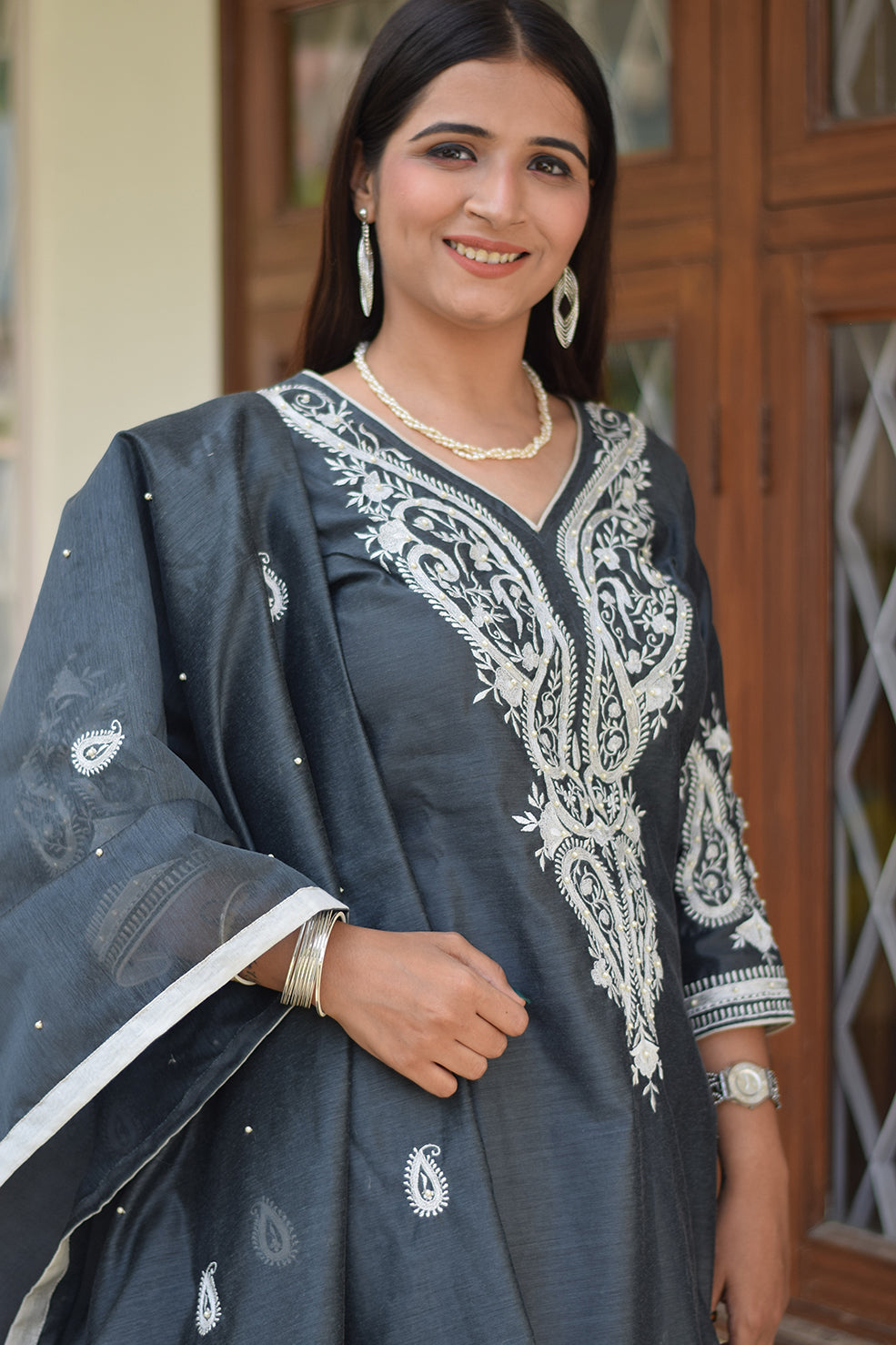 A woman from India dressed in a traditional grey kurta dupatta set.