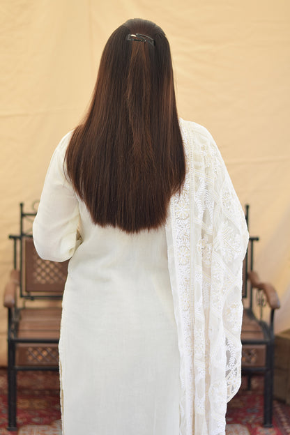 A woman's back in a white georgette kurta, showcasing the delicate chikankari embroidery on the upper back and the elegant drape of the fabric.