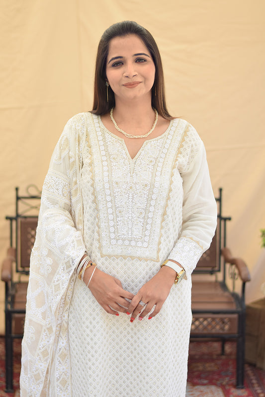 A woman wearing a white georgette chikankari kurta with intricate kikri and kamdani embroidery, paired with matching dupatta and golden trousers